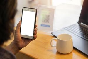Unrecognizable man's hands on cafe or coffee shop desk, working and using the smart phone with isolate screen. photo