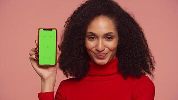 Smiling woman nodding in approval and showing smartphone with green screen video