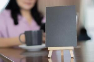 Menu wooden frame standing on wooden table in Bar restaurant cafe with woman blurred behind. photo