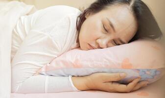 Asian beautiful adult woman with blanket sleeping on bed at home, copy space. photo