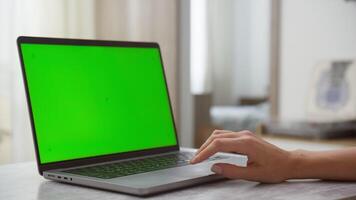 Close-up of female hand using touchpad on laptop with green screen video
