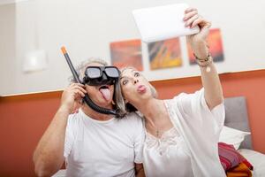 A happy mature couple having fun taking a selfie in bed making faces while wearing a scuba mask photo