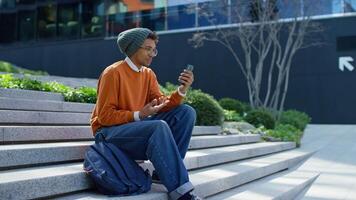 Excited student on call sitting on outdoor steps video