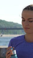 Young woman sipping refreshing water while enjoying a stunning riverside view video