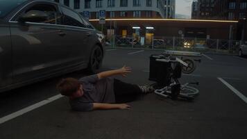 A teenage boy fell from a wheelchair and cannot get up. He is in pain and is lying on the asphalt in the middle of the road after a car accident. video