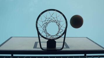 A close-up shot of a basketball being thrown into a basket, with a bounce off the backboard. below video