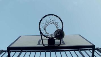 Bottom view of basketball court, with basketball bouncing on ground in an open field under blue sky. team scores a point. directly below video