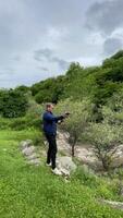 A young adult male enjoying an outdoor shooting activity in lush greenery, capturing adventure and leisure in nature, emphasizing marksmanship and recreation video