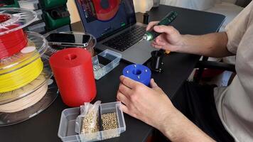 A person works on a 3D printing project, using a laptop and filament spools, showcasing technology and creativity video