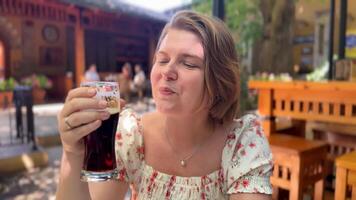 Caucasian woman in her 30s enjoying a refreshing drink outdoors, capturing leisure, summer, and relaxation vibes al fresco, beverage tasting video