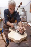expert violin maker in the workshop creating a new violin from a piece of wood photo