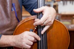 close-up of a luthier's hands playing a newly finished viola to test the sound at work photo