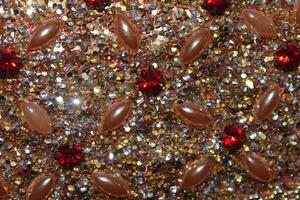 A close-up view of a textured surface adorned with an array of small, sparkling rhinestones in shades of gold and silver. photo