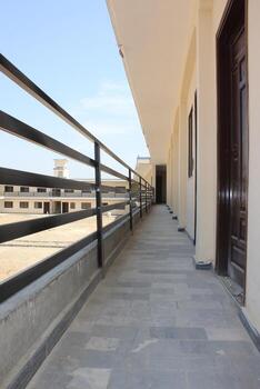 A two-story school building with a flat roof and cream-colored walls that forms a U shape with an open courtyard in the middle. photo