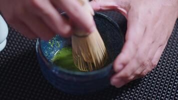 Preparing Matcha Tea Latte at home from measuring, whisking with a bamboo chasen, and pouring into a glass, capturing the soothing ritual of making this traditional Japanese drink. hand video