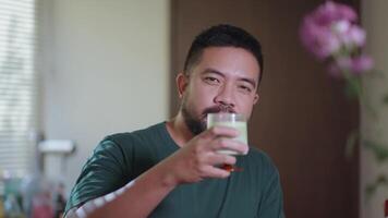 Relaxed scenes of man sipping homemade matcha latte at home. Natural lifestyle moments showing calmness, daily ritual, and enjoyment of a traditional green tea drink look video