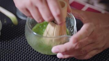 Preparing Matcha Tea Latte at home from measuring, whisking with a bamboo chasen, and pouring into a glass, capturing the soothing ritual of making this traditional Japanese drink. zoom video