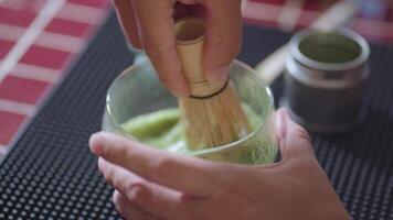 Preparing Matcha Tea Latte at home from measuring, whisking with a bamboo chasen, and pouring into a glass, capturing the soothing ritual of making this traditional Japanese drink. zoom in video