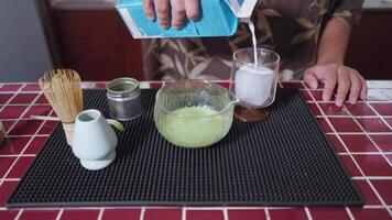 Preparing Matcha Tea Latte at home from measuring, whisking with a bamboo chasen, and pouring into a glass, capturing the soothing ritual of making this traditional Japanese drink.milk to glass of ice video