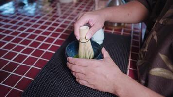 Preparing Matcha Tea Latte at home from measuring, whisking with a bamboo chasen, and pouring into a glass, capturing the soothing ritual of making this traditional Japanese drink. hand closeup video