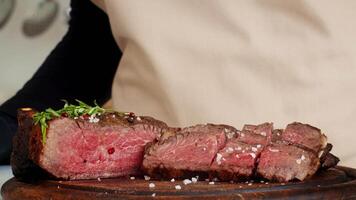 A skilled chef slices into a perfectly cooked steak, revealing its tender pink center. Fresh herbs and seasoning enhance the dish, highlighting healthy cooking practices. video