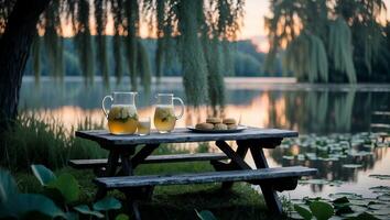 Picnic Table by Lake with Lemonade and Cookies at Dusk photo