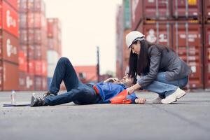 First aid for a container warehouse worker fainted while working in the bright sunlight and hot weather of a container storage yard,146 photo