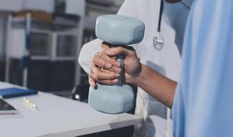 A doctor is holding a dumbbell in front of a laptop photo