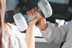 A woman is holding a dumbbell while a man is standing next to her photo