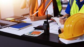 Construction workers at a desk with a laptop and hard hat photo