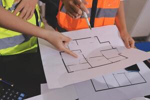 Two people in safety vests are looking at a blueprint photo