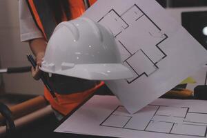A person wearing a hard hat and holding a blueprint photo