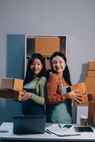 Two women holding boxes and standing in front of a desk photo