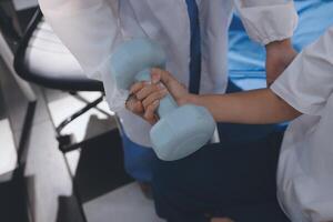 A doctor is holding a dumbbell while a child is sitting on the floor photo