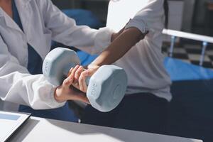 A woman is holding a dumbbell while a doctor is standing next to her photo