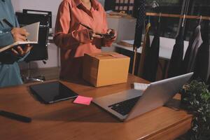 Two people standing at a desk with a laptop and a box photo