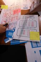 A person is working on a laptop with a bunch of paper and sticky notes photo