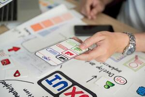 User Interface Design. Hand holding smartphone with app features during brainstorming session. photo