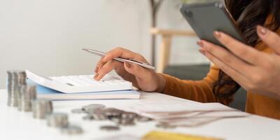 Expense Calculation and Financial Awareness. Woman using smartphone and calculator for budgeting. photo