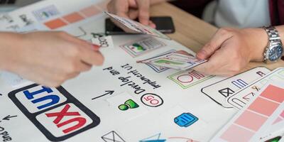 ux ui diseño proceso. manos intercambiando diseño tarjetas durante un creativo reunión. foto