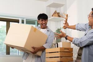 Playful gay couple enjoying unpacking boxes in their shared space photo