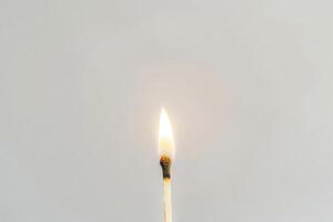 Single burning matchstick against white background. Concept of ignition, heat, energy, simplicity, and minimalism. Copy space photo