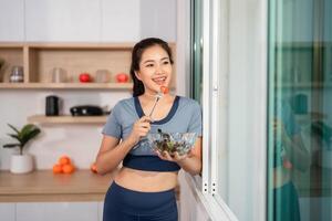 ESG and Nutrition. Happy woman enjoying a salad while standing by the window. photo