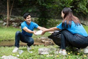 Volunteer Team Collecting Waste in Nature. Two individuals engaged in a cleanup effort in a lush setting. photo