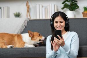 Digital Engagement and Pet Love. Woman smiling while using smartphone with her dog nearby at home. photo