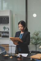 A woman in a business suit is standing at a desk with a clipboard photo