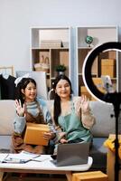 Two women sitting on a couch with a camera and a laptop photo