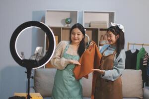 Two women in aprons are holding a camera and a phone photo