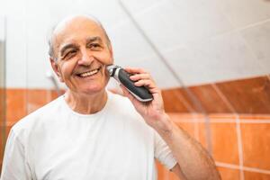 Senior gentleman with gray hair and a neat appearance using an electric shaver, focusing on facial care and personal hygiene. photo