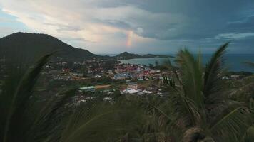 Rainbow in the sky over ocean of tropical paradise island with palm trees evening cinematic aerial shot. Rainbow in the sky over sea and mountains. Tropical stormy cloudy sky with rainbow after rain video